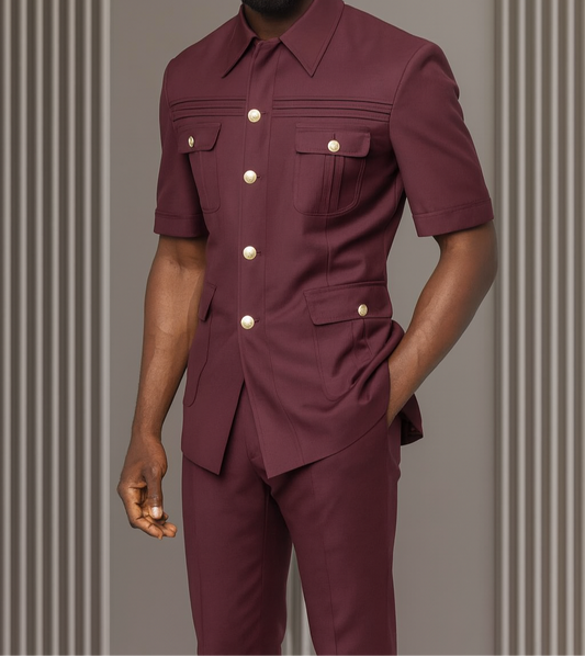 Man wearing a maroon outfit with gold buttons against a gray background