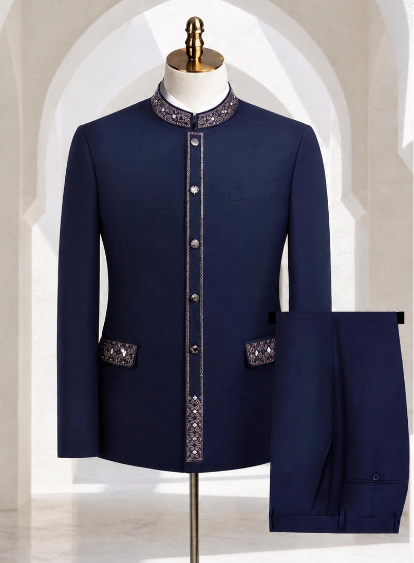A navy blue men's suit set displayed on a mannequin, featuring a jacket with ornate silver and white embroidery on the collar, front placket, and pocket flaps, paired with matching trousers shown folded on the right.