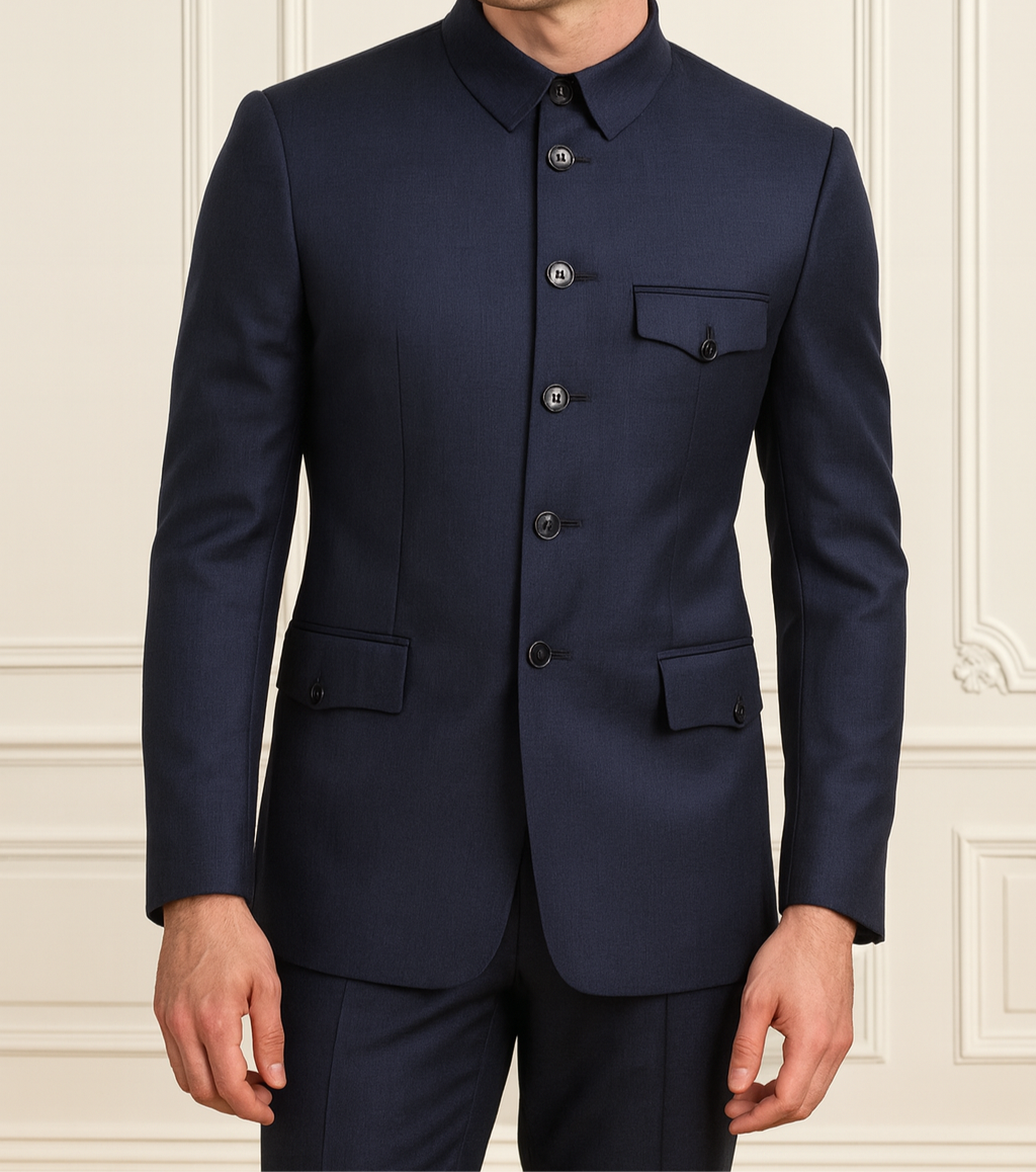 Man wearing a navy blue suit against a light-colored wall.