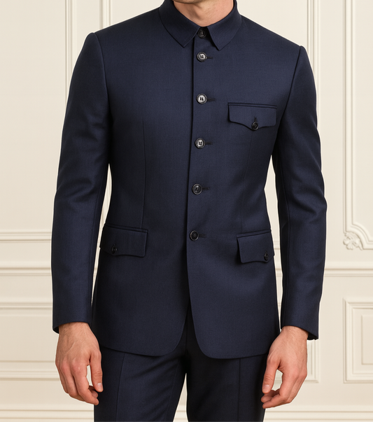 Man wearing a navy blue suit against a light-colored wall.