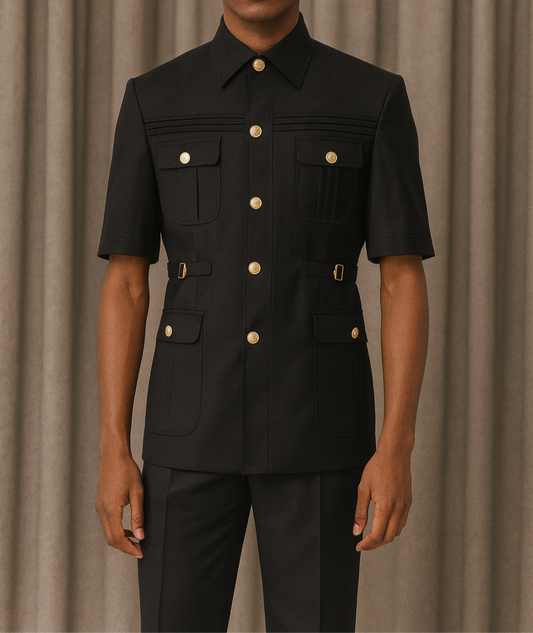 Man wearing a black outfit with gold buttons against a beige curtain background