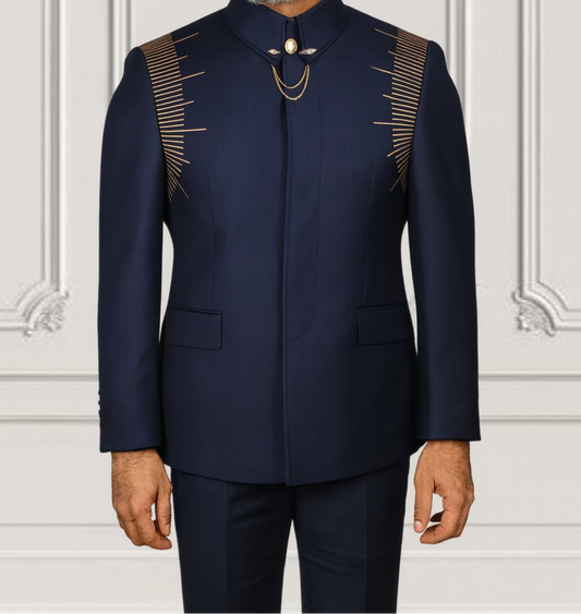 Man wearing a navy blue suit with gold accents against a white wall.