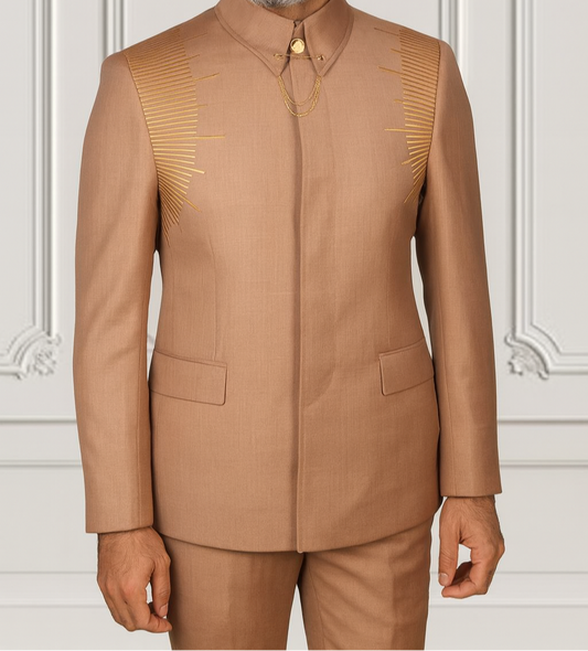 Man wearing a brown traditional outfit against a white paneled wall.